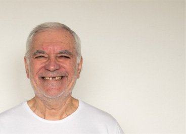A smiling man assessing dentures with his dentist