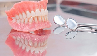 Two full dentures in Baytown, TX next to a dental mirror