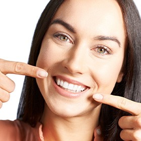 A woman pointing to her newly whitened teeth