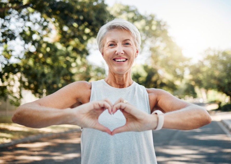 Smiling lady makes shape of heart with her hands