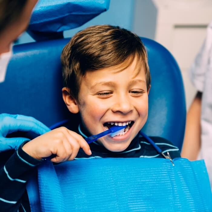 Child practicing tooth brushing during dental checkup and teeth cleaning visit