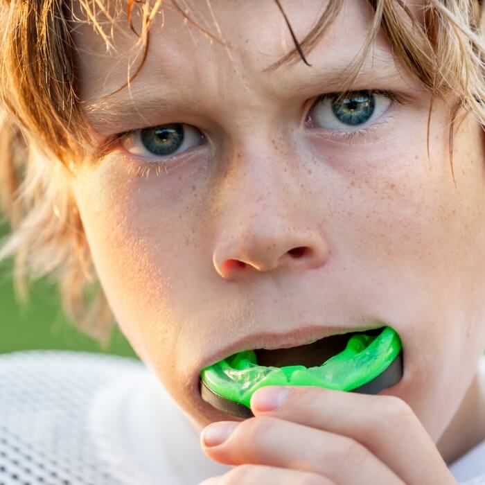 Teen placing athletic mouthguard