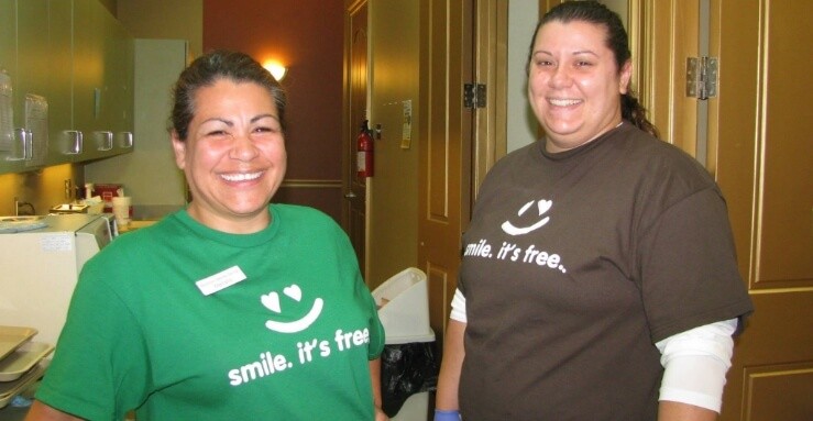 Two dental team members wearing matching shirts at a community event