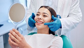 Woman with beautiful smile looking at reflection in small mirror