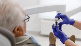 older patient sitting in the chair and talking to the dentist about dental implants