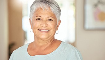 Senior woman in light blue shirt smiling at home