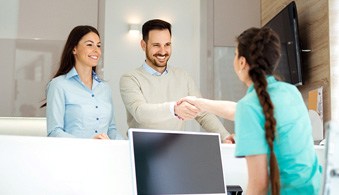 Man smiling and shaking receptionist’s hand