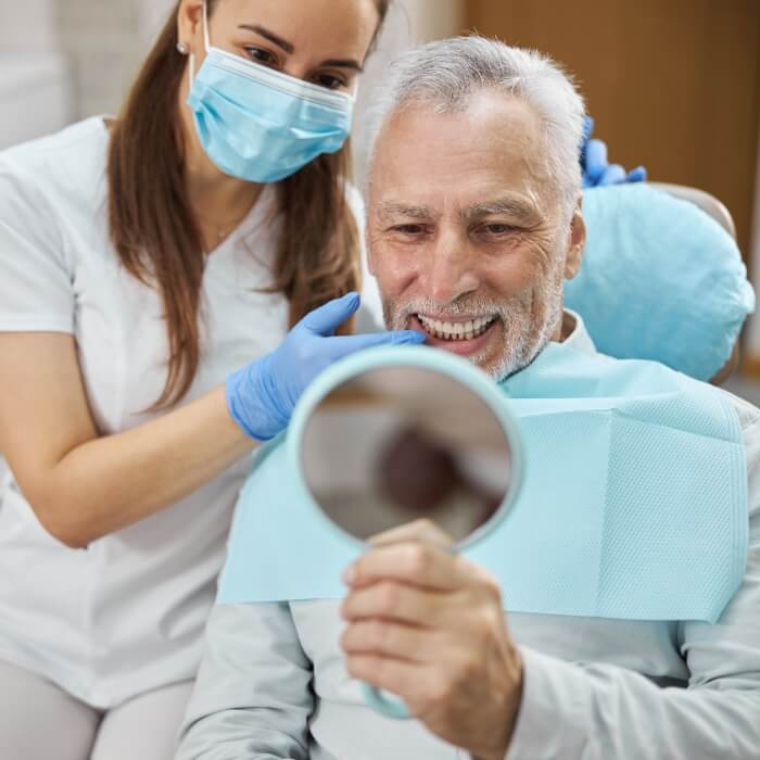 Dentist and dental patients looking at smiles in mirror