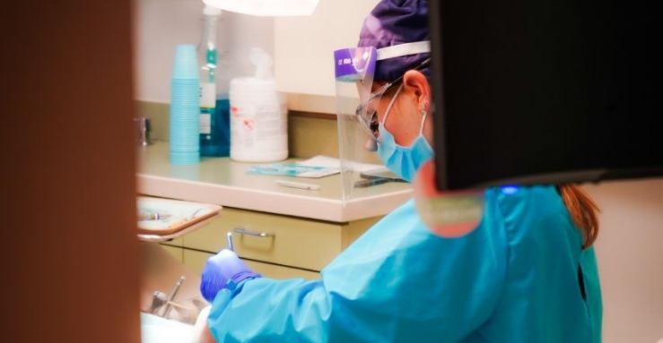 Baytown dentist treating dental patient while wearing appropriate protective gear