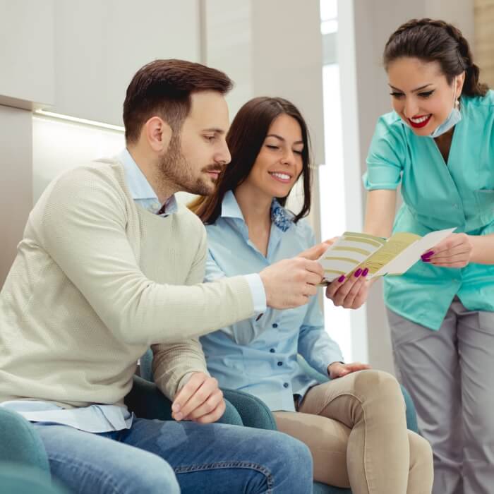 Dental team member and dentistry patients reviewing dental insurance coverage