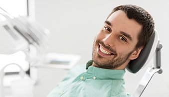 Man with facial hair smiling and sitting in dental chair