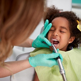 A dentist examining a young girl for a dental checkup in Mineola