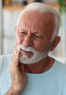 a man holding his cheek due to tooth pain