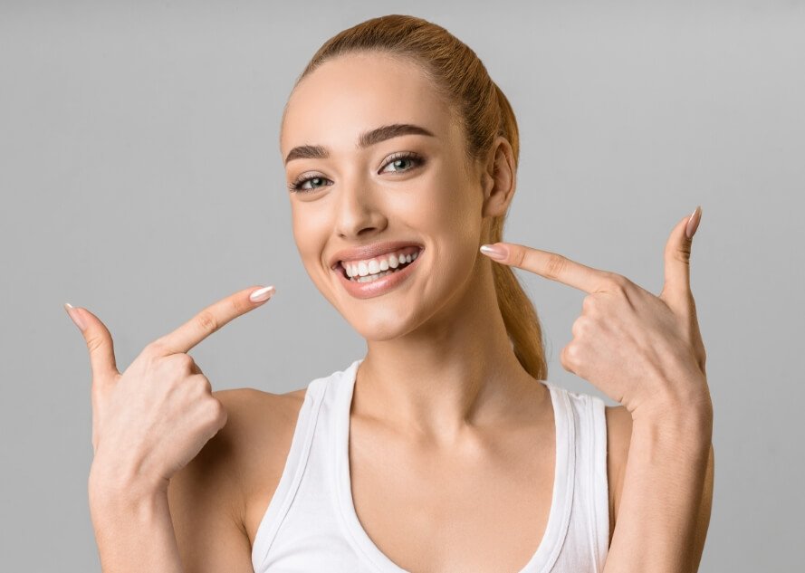 Woman pointing to healthy smile after gum disease treatment