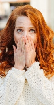 Woman in need of gum disease treatment covering her mouth