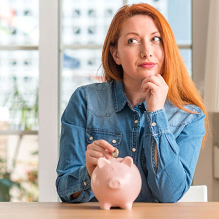 woman putting a coin into a piggy bank