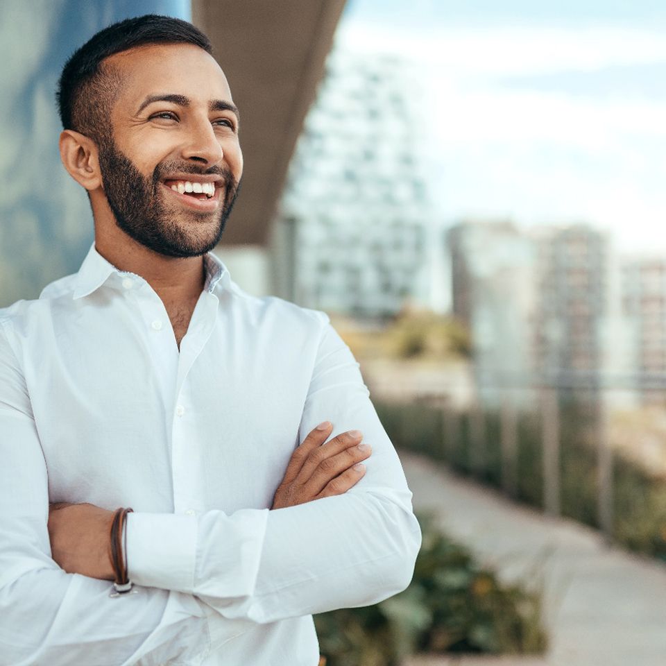 Man in white shirt smiling with arms folded