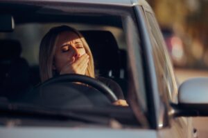 Woman yawning while driving car.